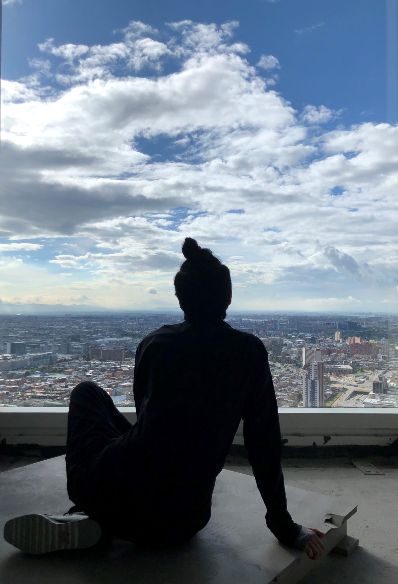 Fotografia d'una persona asseguda en una terrassa observant la ciutat