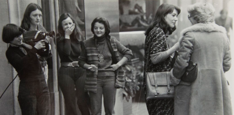Fotografía de una entrevista a una mujer en la calle con un equipo de vídeo y jóvenes riendo y observando la acción, Video-Nou, 1977