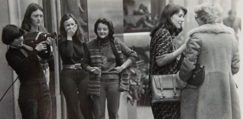 Photograph of an interview with a woman on the street with a video crew and young people laughing and watching the action, Video-Nou, 1977