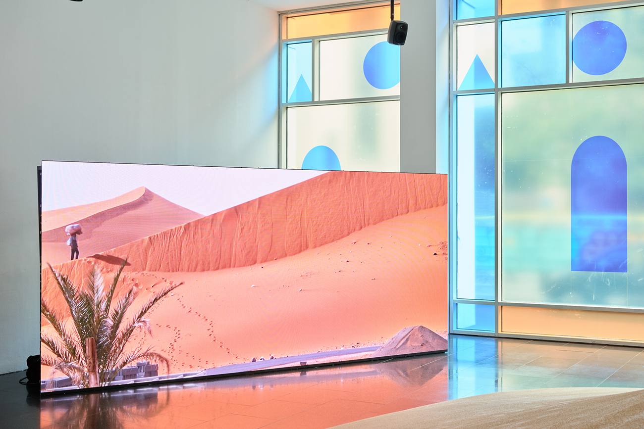 A una de les sales del MACBA, una pantalla de gran format projecta la imatge d'un home que camina per un desert de sorra vermellosa.