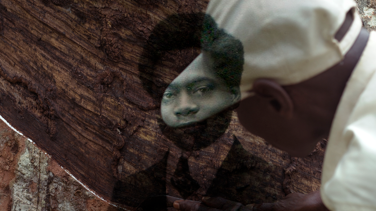 Fotograma de la película "L’Arbre de l’authenticité", en el que un leñador congoleño tala un árbol. Sobre la escena, se superpone la imagen de carnet de un niño vestido con traje y corbata.