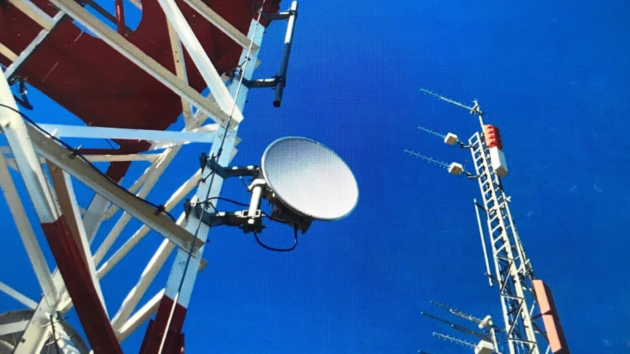 Plano detalle de dos antenas de telefonía móvil frente a un cielo azul.